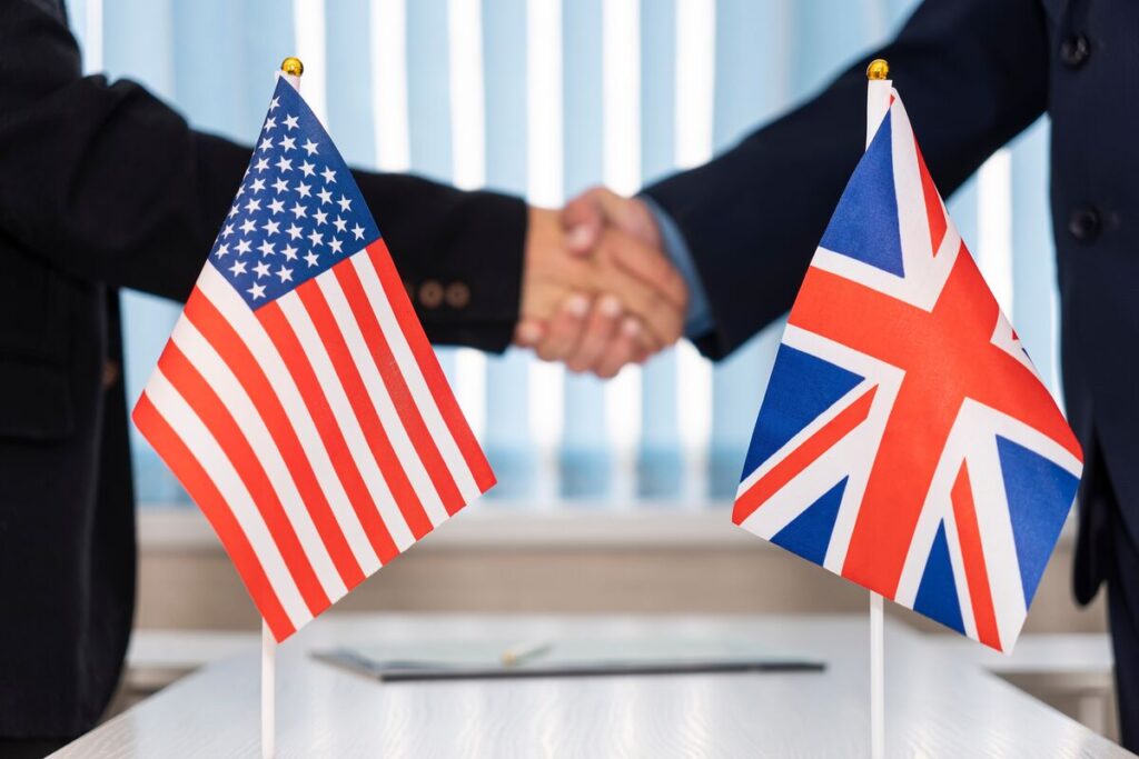 American and British flags in front of two men shaking hands