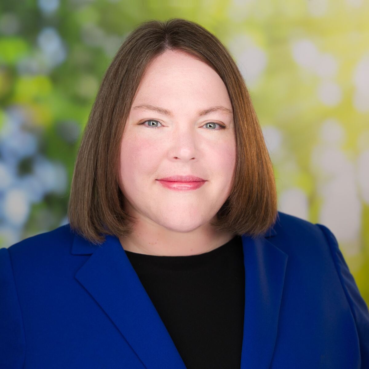 Woman with brown hair, black shirt and blue jacket.
